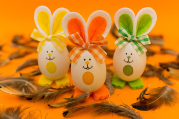 Three Easter eggs with bunny ears on spring yellow background.