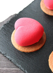 Pink macaroons in the shape of a heart on a black stone plate, a sweet gift for Valentine's Day