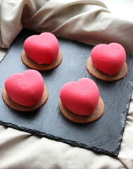Pink macaroons in the shape of a heart on a black stone plate, a sweet gift for Valentine's Day