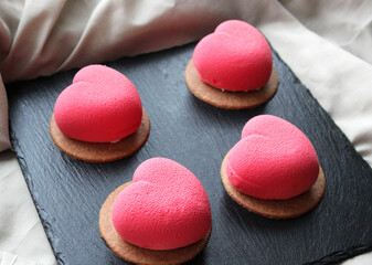 Pink macaroons in the shape of a heart on a black stone plate, a sweet gift for Valentine's Day
