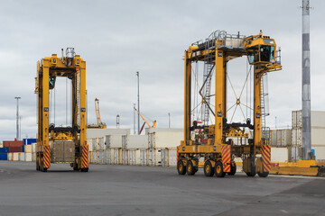 Two straddle carriers, giant vehicles used to move shipping containers, in a cargo terminal