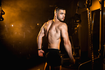 Fototapeta na wymiar Young man athlete posing in the gym, stimulates to go in for sports