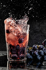 Fresh grape juice and ice cubes on black background