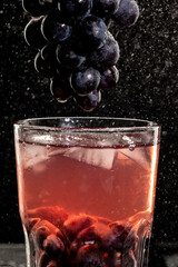 Fresh grape juice and ice cubes on black background