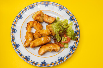 fried squid with fried potato and salad on the plate