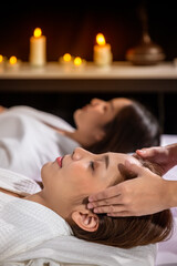 Obraz na płótnie Canvas Beautiful young Asian woman enjoy head massage in tranquil spa salon, with candle.