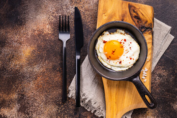Fried egg in the pan on a dark rustic background. Still life- fast food. 