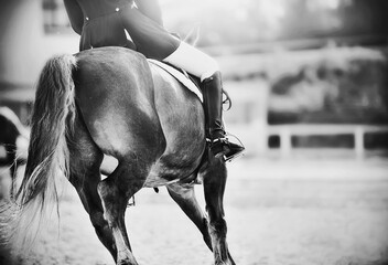 A black-and-white image of a fast horse with a rider in the saddle, galloping forward in the...
