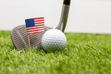 Golf ball and iron are on green grass