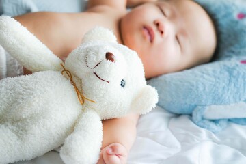 Newborn baby sleep witha doll on the bed,Cute little Asian 5 months sleeping in bed while hugging bear, Daytime sleep.
