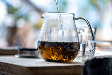 Pouring hot water into teapot with tea leaves.
