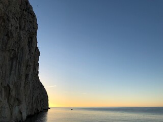 Amanecer con el mar Mediterráneo de Calpe en calma con un barquito navegando