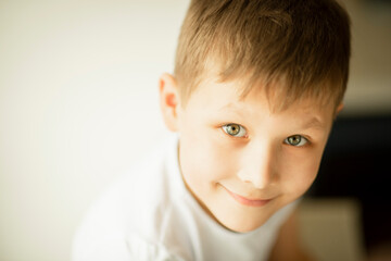 a boy in a light T-shirt on a light background smiles