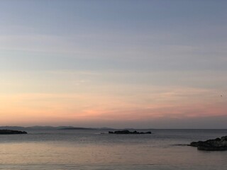 Fototapeta na wymiar Atardecer con el cielo anaranjado y rosado en la playa cerca del mar