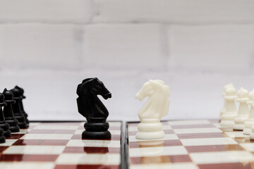Black and white chess knights opposite each other on a chessboard. Concept of chess strategy, opposition, start of the fight, duel © RollAndSnap