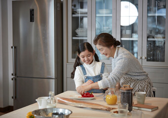 Happy adorable little child girl in apron enjoying cooking homemade pastry together with grandmother at home.