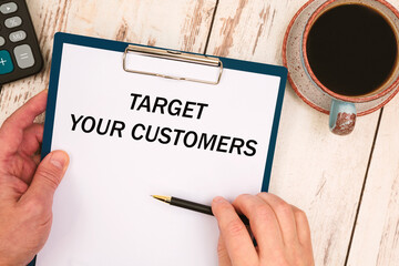 Paper with text Target your customers on the table, calculator and cup of coffee