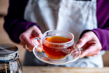 Woman holding cup of hot black tea.
