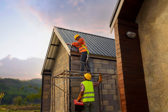 Two construction workers installing a roof on a building, Thailand