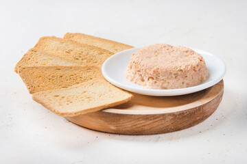 Smoked salmon and soft cheese spread pate with brown bread on white background.