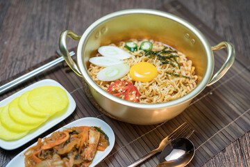 Korean traditional Ramyeon noodle  with egg yolk, chilli, kimchi in a traditional korean noodle pot, Spicy Korean Ramyeon instant noodle a traditional dish.