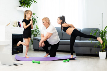 Obraz premium grandmother and children exercising workout at home near the window in room