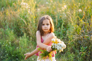 Naklejka na ściany i meble Portrait of a little girl with flowers in the field
