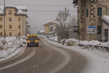 Fototapeta premium Snowy road in the village of Vodo di Cadore in Italy during heavy snow. One van is driving on a snow covered street.