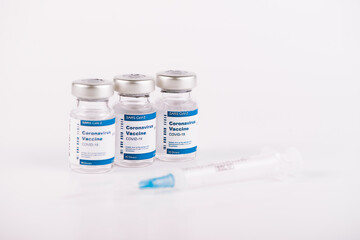 three Covid-19 vaccine vials and syringe with white background