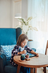 Portrait of a smart preschool kid in casual clothing which draws something on tablet using a pencil...