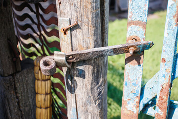 The simplest rustic door lock. A rusty padlock on a wooden door of an old rustic building. Old cracked wood planks burnt out in the sun.