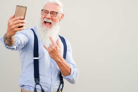 Portrait of attractive hipster man. Positive gray-haired pensioner making selfie. Technology and elderly concept.