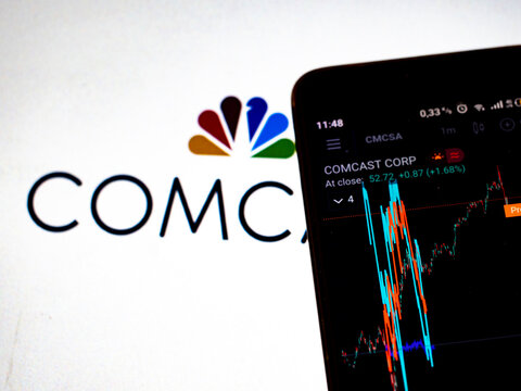 In this photo illustration the stock market information of Comcast Corporation displays on a smartphone while the logo of Comcast Corporation  displays as the background.
