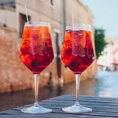 Two glasses of Spritz Veneziano cocktail served near the Venetian canal.  Popular italian summer aperitif drink. Venice background.