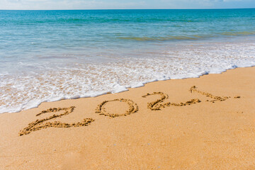 2021 year sign hand written sandy beach sunny outdoors background.