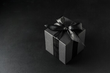 Black gift box with bow on black background