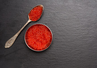 red caviar of chum salmon in a metal spoon on a black background