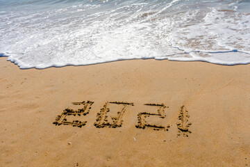 2021 year sign hand written sandy beach sunny outdoors background.