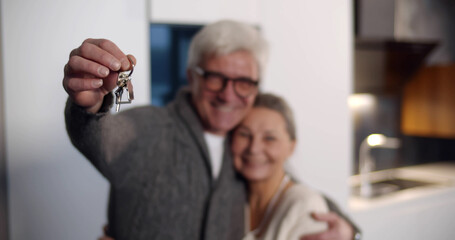 Senior man holding keys and embracing wife in new house
