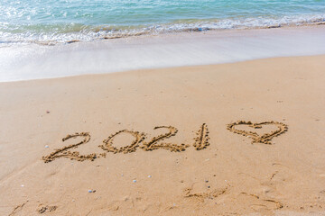 2021 year and love heart sign hand written sandy beach outdoors seascape background.
