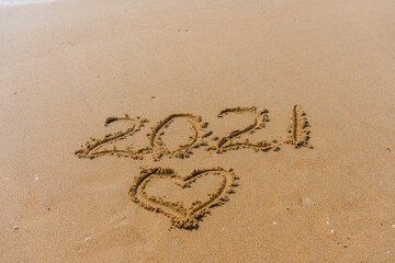 2021 year and love heart sign hand written sandy beach outdoors seascape background.