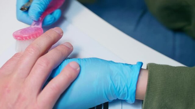 Manicurist uses metal nippers to remove dry skin of cuticle around nails. Processe of manicure.