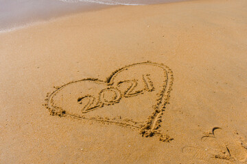 2021 year and love heart sign hand written sandy beach outdoors seascape background.