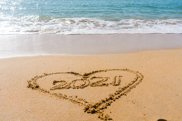 2021 year and love heart sign hand written sandy beach outdoors seascape background.