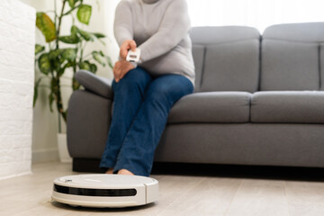 senior woman lying on couch and Robot vacuum cleaner in the room