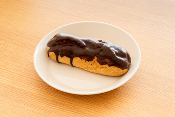 A chocolate eclair on a white dish