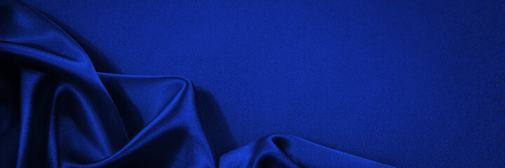 Dark blue silk satin background. Copy space for text or product. Wavy soft folds on shiny fabric....