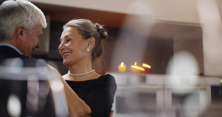 Aged caucasian couple enjoying time at home together dancing in kitchen and smiling