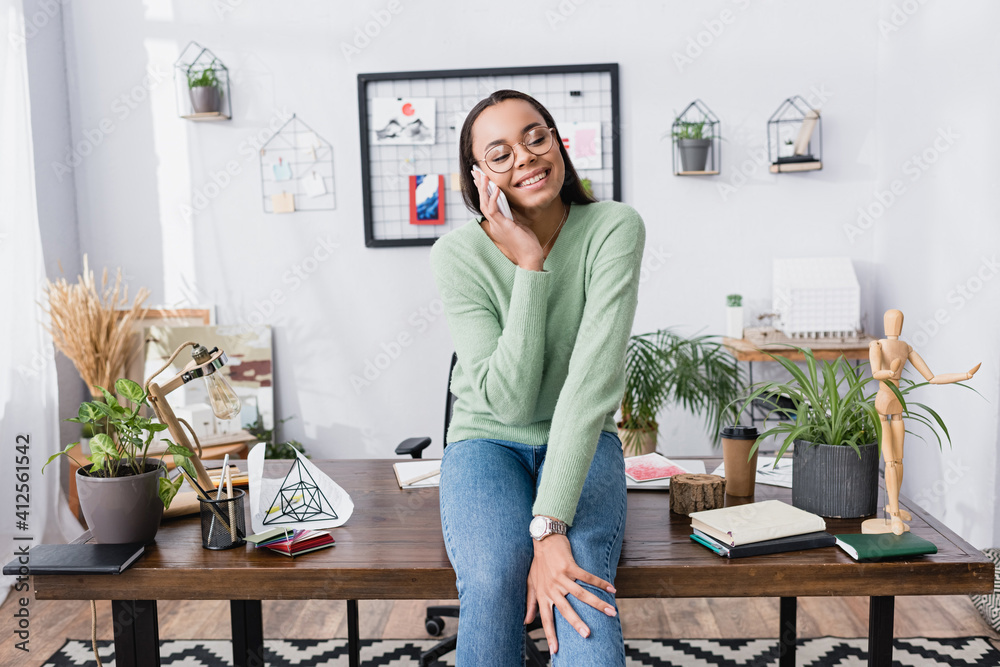 Canvas Prints happy african american architect talking on smartphone while sitting on desk at home studio