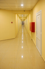 Interior of a long yellow hotel corridor